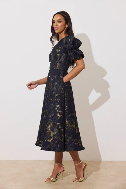 8th Sign Callie Button Dress Midnight Blue Gold on model in a gold floral print. Shop 8th Sign at Dotique.