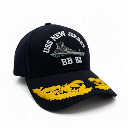 A black baseball hat with gold embroidery featuring the USS New Jersey and the hull number BB 62 on the front, and yellow flame designs on the brim.