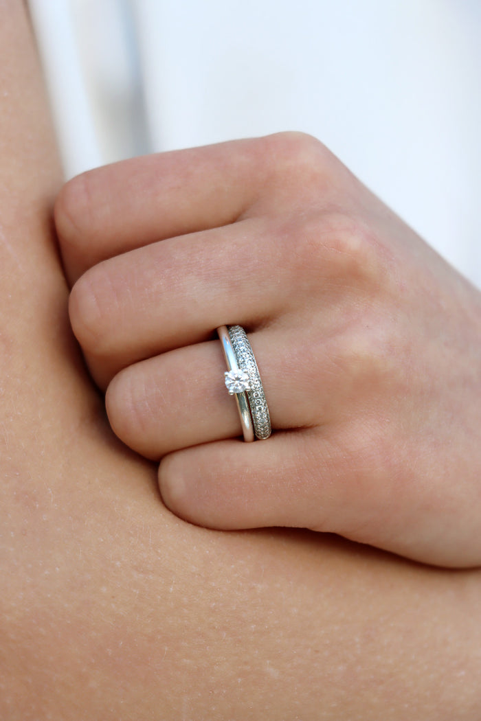 Tjej som bär ett set med vigselring och förlovningsring i silver med diamanter.