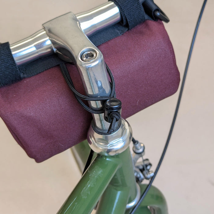 back view of maroon handlebar bag on bike with bungee strap