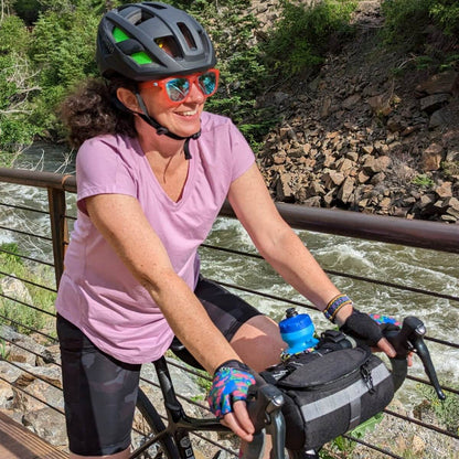 Cyclist by a river using a handlebar bag.