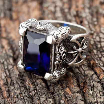 A large sterling silver dragon claw ring holding a massive rectangular sapphire-blue stone on a white background.