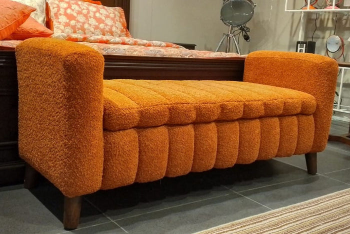 Orange tufted upholstered ottoman bench with rounded sides and sturdy wooden legs
