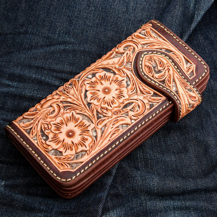The brown floral biker wallet resting on blue denim jeans to show scale and style.
