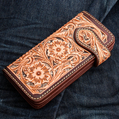 The brown floral biker wallet resting on blue denim jeans to show scale and style.