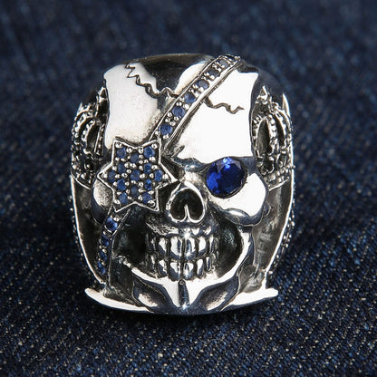 The blue eye patch skull ring displayed on a dark blue denim texture.