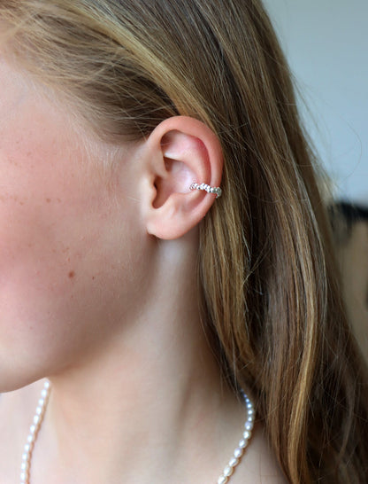 Tjej som bär en ear cuff mitt på örat. Ear cuff i äkta silver med små silverkulor.