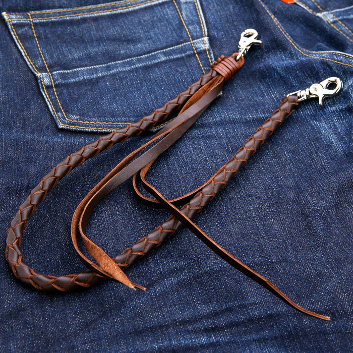 The full length of the braided dark brown leather wallet chain with silver clasps, shown laid flat on a pair of dark denim jeans.