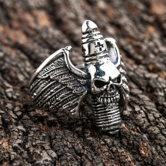 Angled view of the gothic statement ring displaying the central skull, textured wings, and ribbed cross detail on a wood surface.