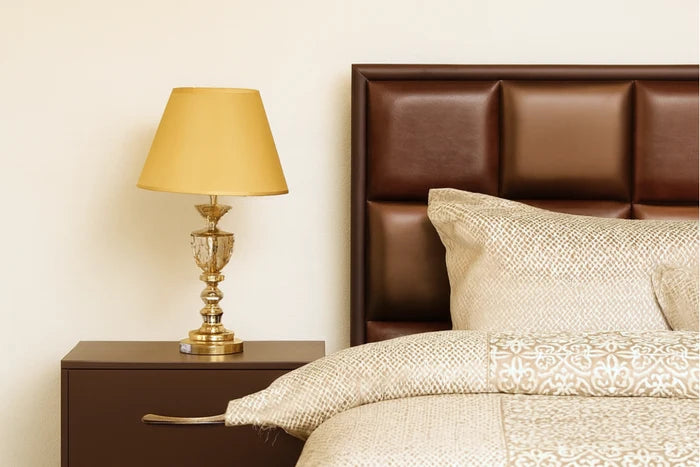 Brown upholstered bed with paneled headboard, side table, and table lamp