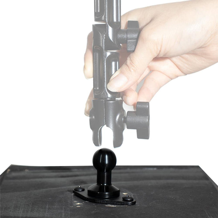 A hand adjusts a black clamp mount above a 20mm ball mount attached to a flat black surface, showing how the Arkon HD Series clamp connects to the ball joint using the Diamond 2-Hole AMPS to 20mm Ball Adapter.