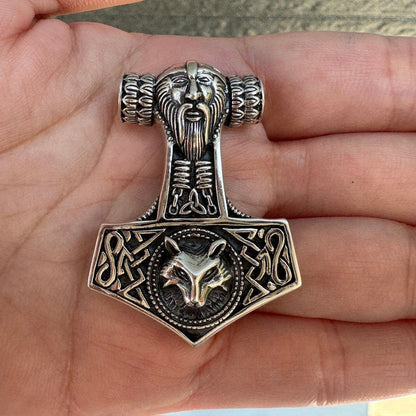 Open palm holding the carved .925 silver Norse pendant, revealing the scale of the bearded Thor and wolf head details.