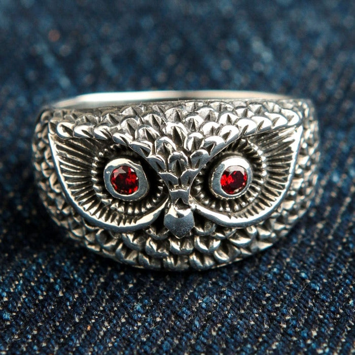 Sterling silver owl face ring with fiery red garnet eyes photographed on blue denim fabric
