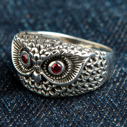 Three-quarter view of 925 sterling silver owl ring displaying oxidized feather details and red garnet eyes
