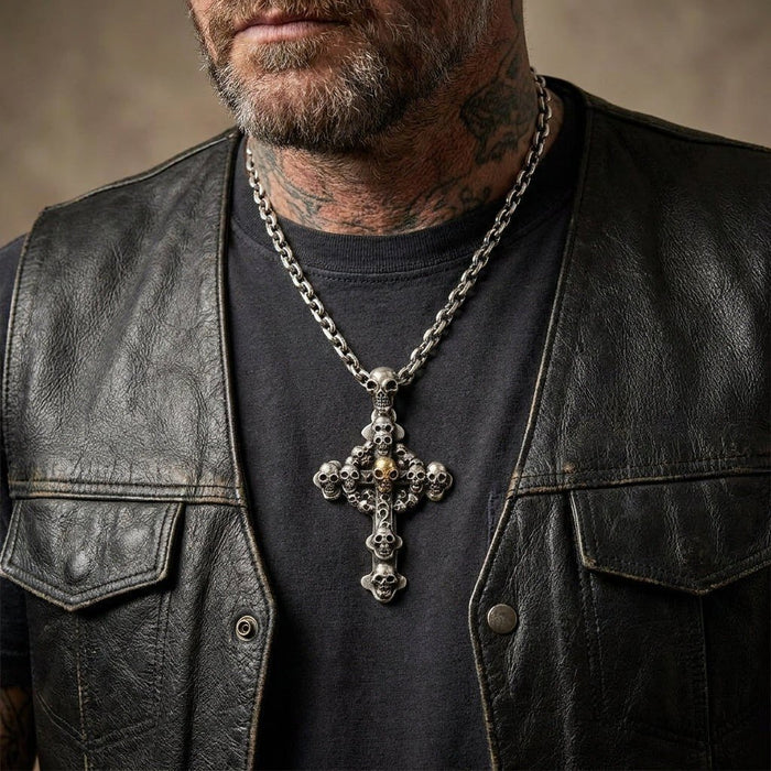 Lifestyle view of a tattooed man wearing the oxidized silver skull cross pendant on a heavy chain over a leather vest.