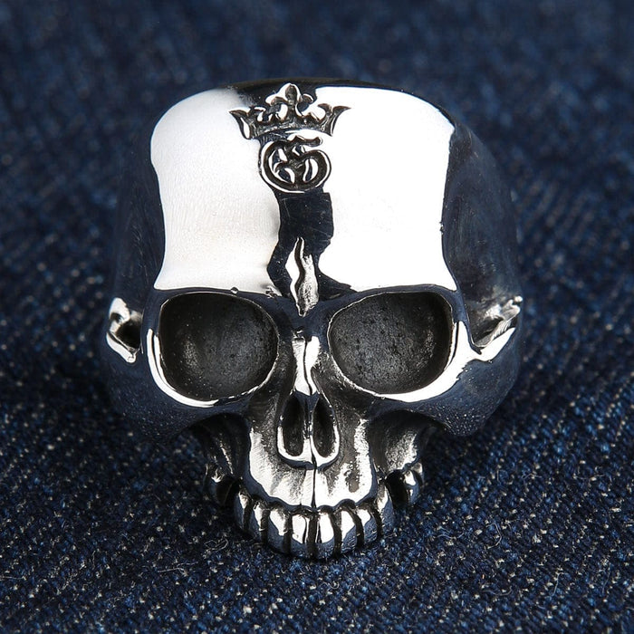 Polished front face of the handcrafted .925 silver skull ring on dark denim, highlighting the detailed crown engraving.