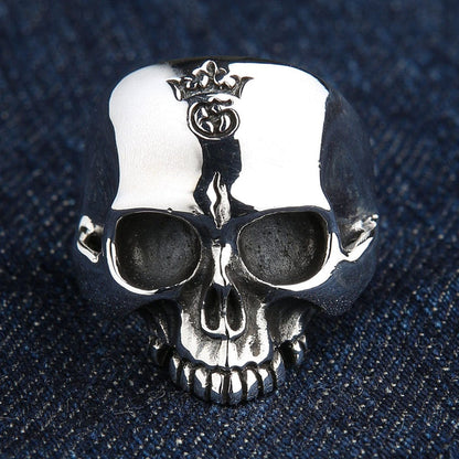 Polished front face of the handcrafted .925 silver skull ring on dark denim, highlighting the detailed crown engraving.