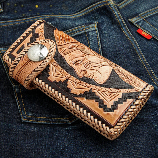 The hand-carved Native American leather wallet with an Indian chief design, closed on a pair of blue jeans.