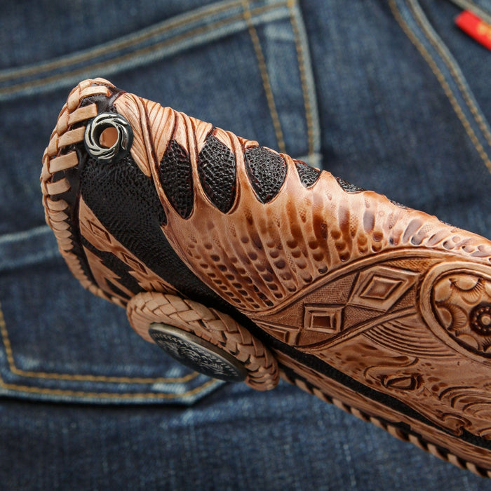 A close-up of the sterling silver grommet on the hand-braided edge of the carved leather wallet.
