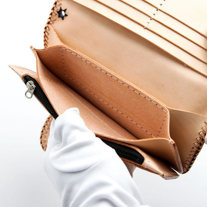 Gloved hands holding open the handmade leather wallet to display the zippered coin compartment.