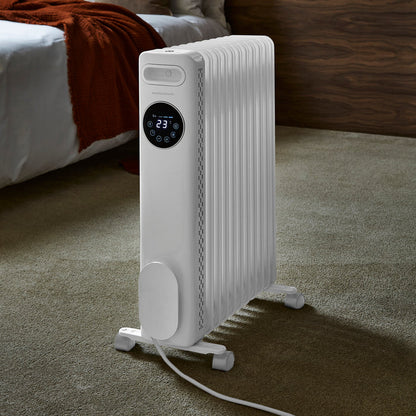 White electric radiator with digital display on a carpeted floor, bedroom setting.