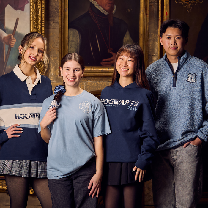 Four people wearing Hogwarts-themed clothing in a room with classical painting.