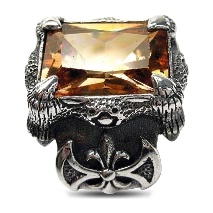 Glowing golden imperial topaz stone held by silver claws above a fleur-de-lis emblem on a men's gothic silver ring