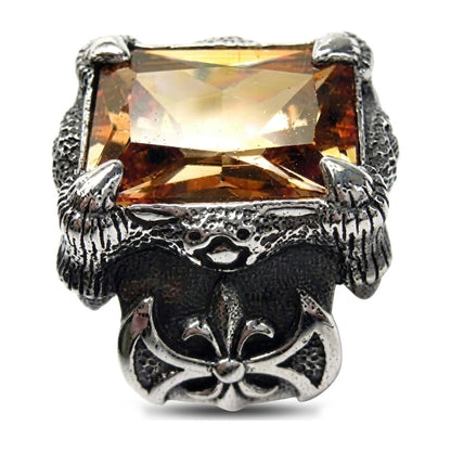 Glowing golden imperial topaz stone held by silver claws above a fleur-de-lis emblem on a men's gothic silver ring