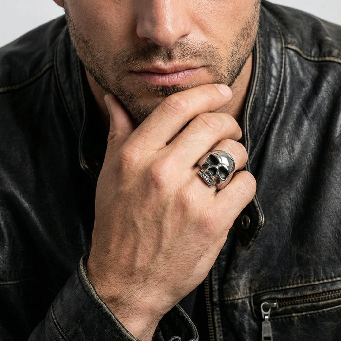 Sterling silver skull ring worn on a man's middle finger with a distressed leather jacket in the background
