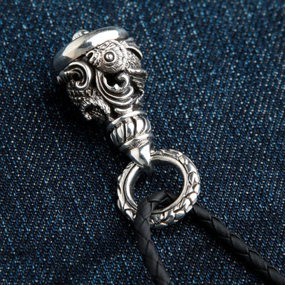 Handcrafted Koi fish biker bell in oxidized sterling silver displayed on blue denim fabric