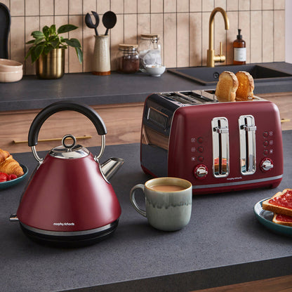 Red kettle and toaster on a kitchen counter with a cup of coffee and toast.