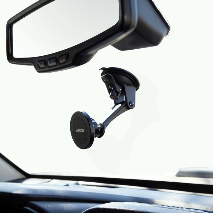 The Magnetic Phone Holder with Sticky Suction Mount - MagSafe Compatible attaches below the rearview mirror, keeping your phone secure while leaving the dashboard, car interior, and mirror clearly visible.