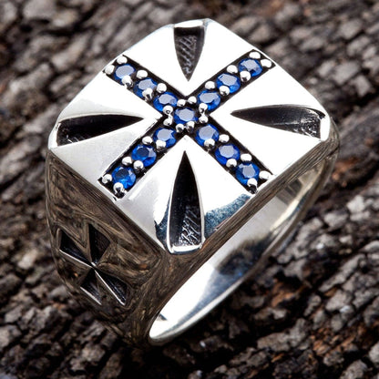 A handcrafted sterling silver Maltese cross ring with deep blue CZ stones and a high-polish finish.