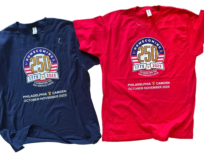 Two t-shirts, one navy and one red, with a homecoming design on a wooden surface.