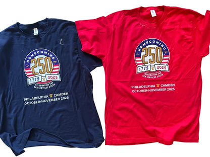 Two t-shirts, one navy and one red, with a homecoming design on a wooden surface.