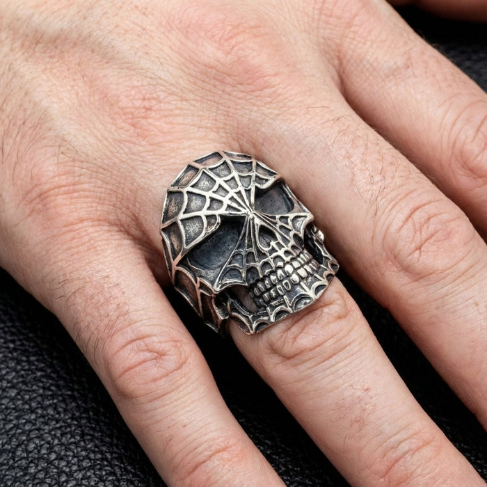 Large spider web skull ring worn on a man's finger for scale