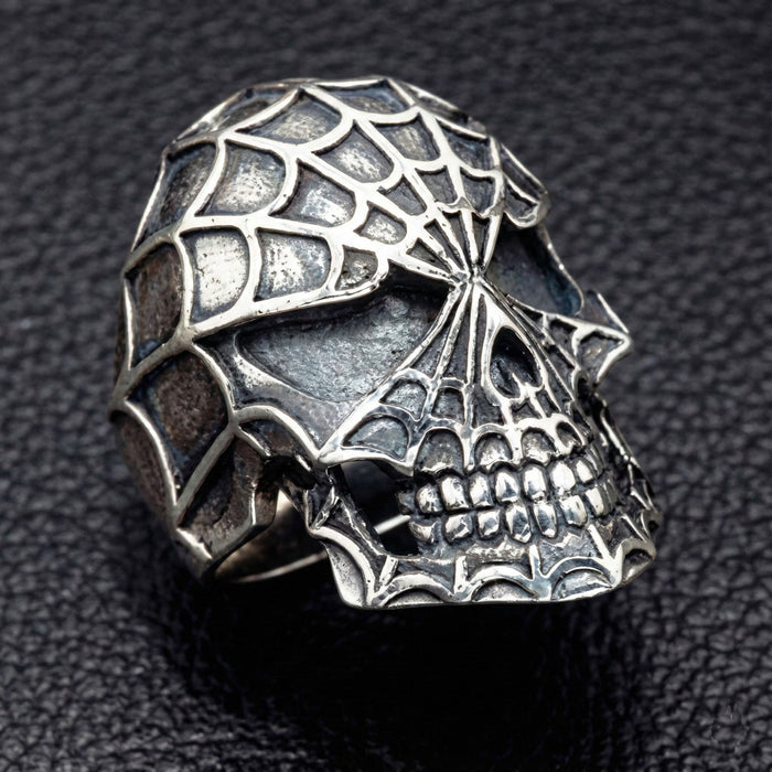 Side profile of silver skull ring showing jaw and web texture