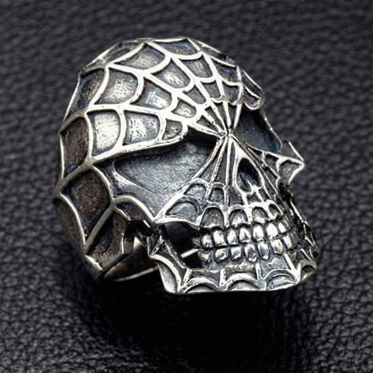 Side profile of silver skull ring showing jaw and web texture