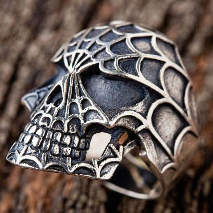 Angled view of handcrafted silver skull ring showing web details