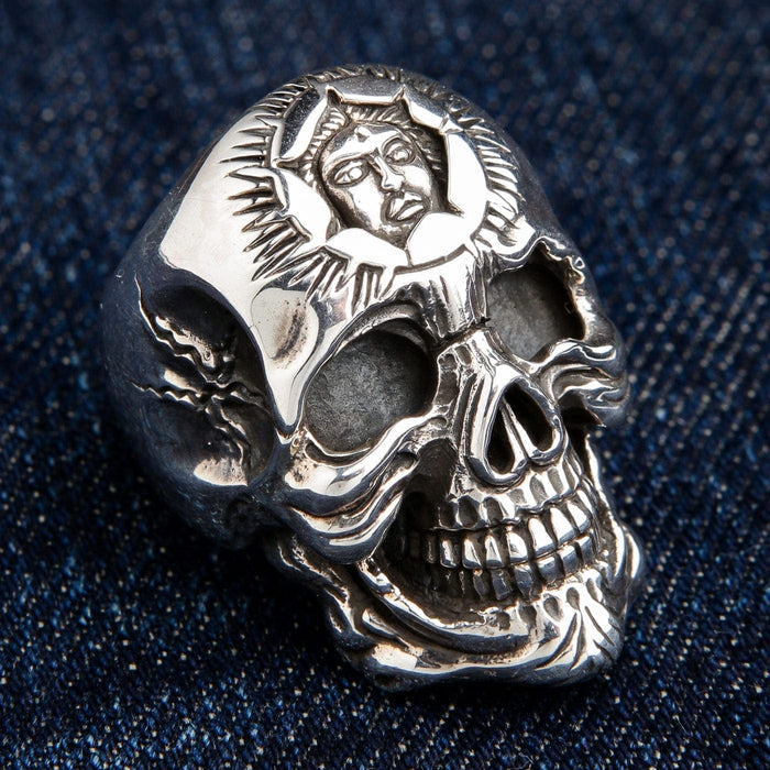 An angled view of the handcrafted biker skull ring with a sun god design, highlighting the oxidized eye sockets.